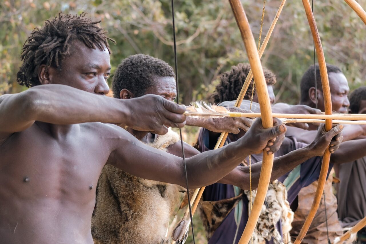 A line of Hadzabe archers walking through the Eyasi bushland